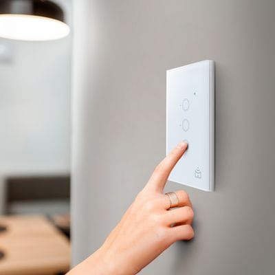 Positivo Smart instalado em uma parede residencial controlando a iluminação por aplicativo e comando de voz.