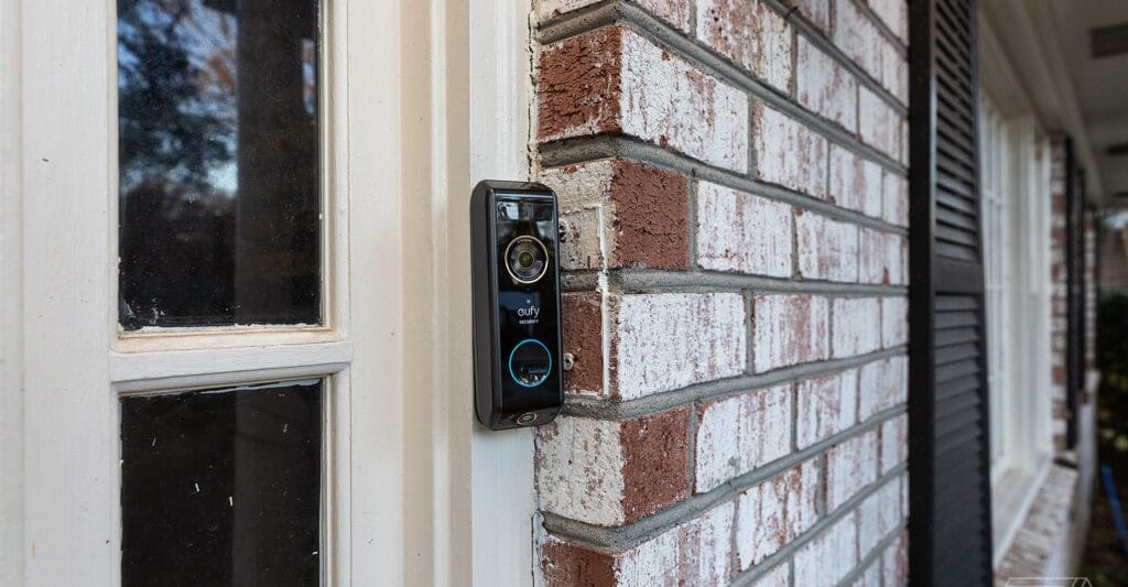 Eufy Video Doorbell Dual instalada em uma entrada residencial mostrando câmera dupla captando visitante e pacote na porta com visão ampliada
